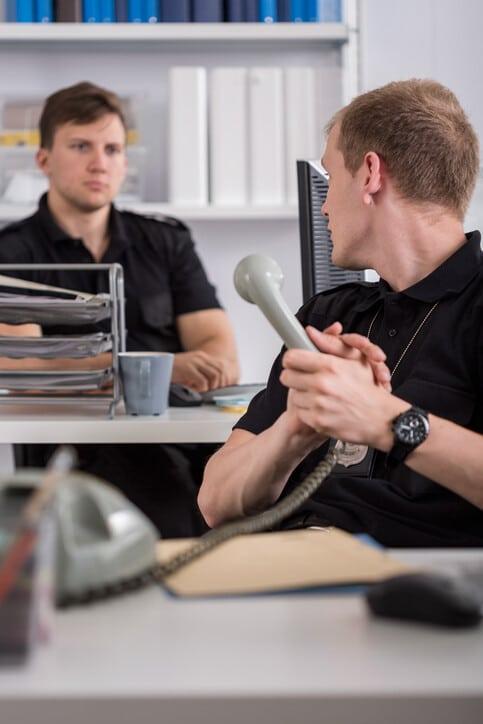 Policeman is talking on stationary telephone at work