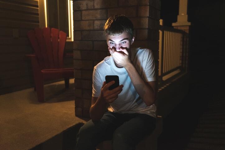Shocked teenager on mobile phone at night.