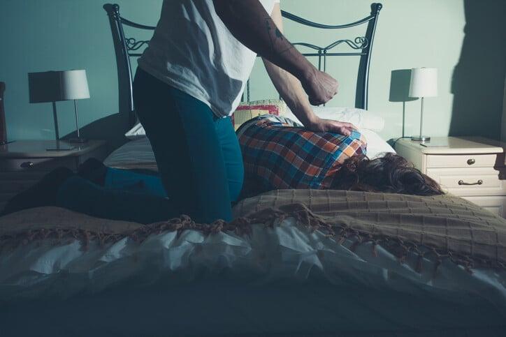 A man is beating his wife on a bed