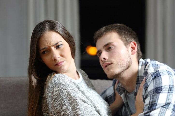 Insistent man trying to get sex and his worried girlfriend denying on a couch in the night at home