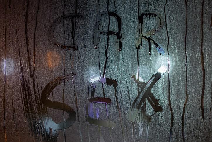 the words car sex written by finger on sweaty night window glass - close-up