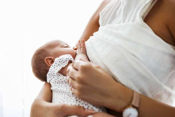 Mother breastfeeding and hugging newborn baby