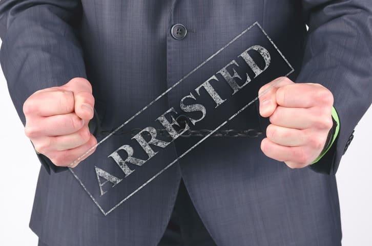 Handcuffs on a businessman hands isolated on a white background.
