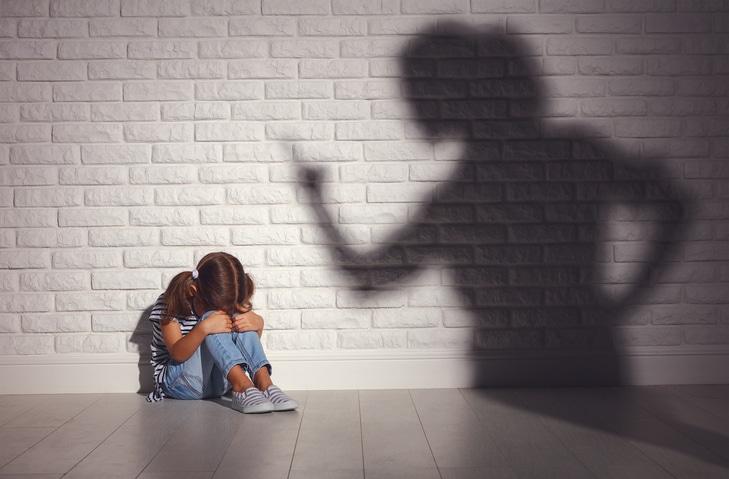 domestic violence. angry mother scolds frightened daughter sitting on floor