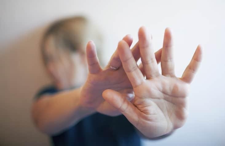 A young woman protects herself by hand